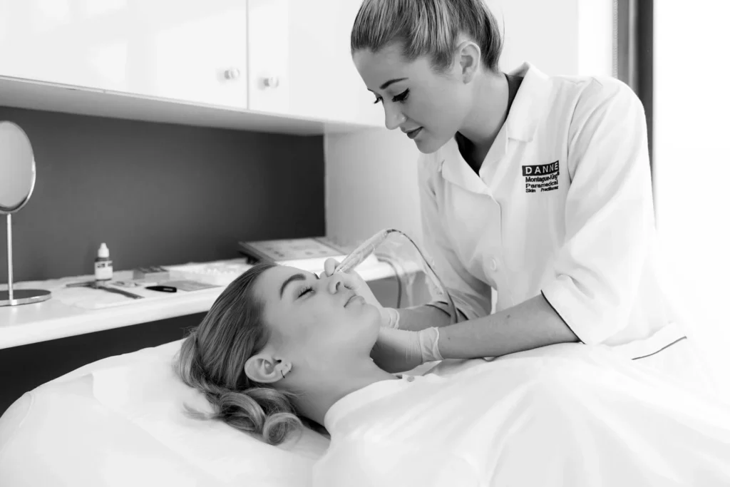 Professional performing cosmetic skin treatment on client lying in clinic.