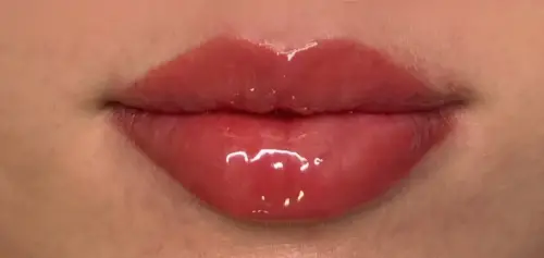 Glossy lips with freshly applied semi-permanent tint in deep pink.