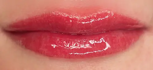 Close-up of lips with glossy bright red permanent lip blush.