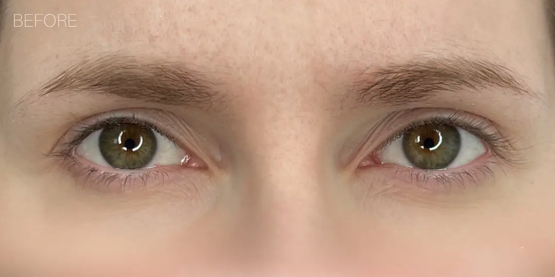 Close-up of natural green eyes with unstyled, lighter eyebrows.