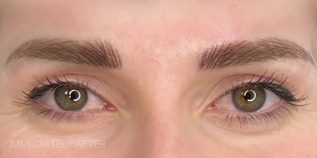 Close-up of green eyes with freshly shaped, darkened eyebrows.